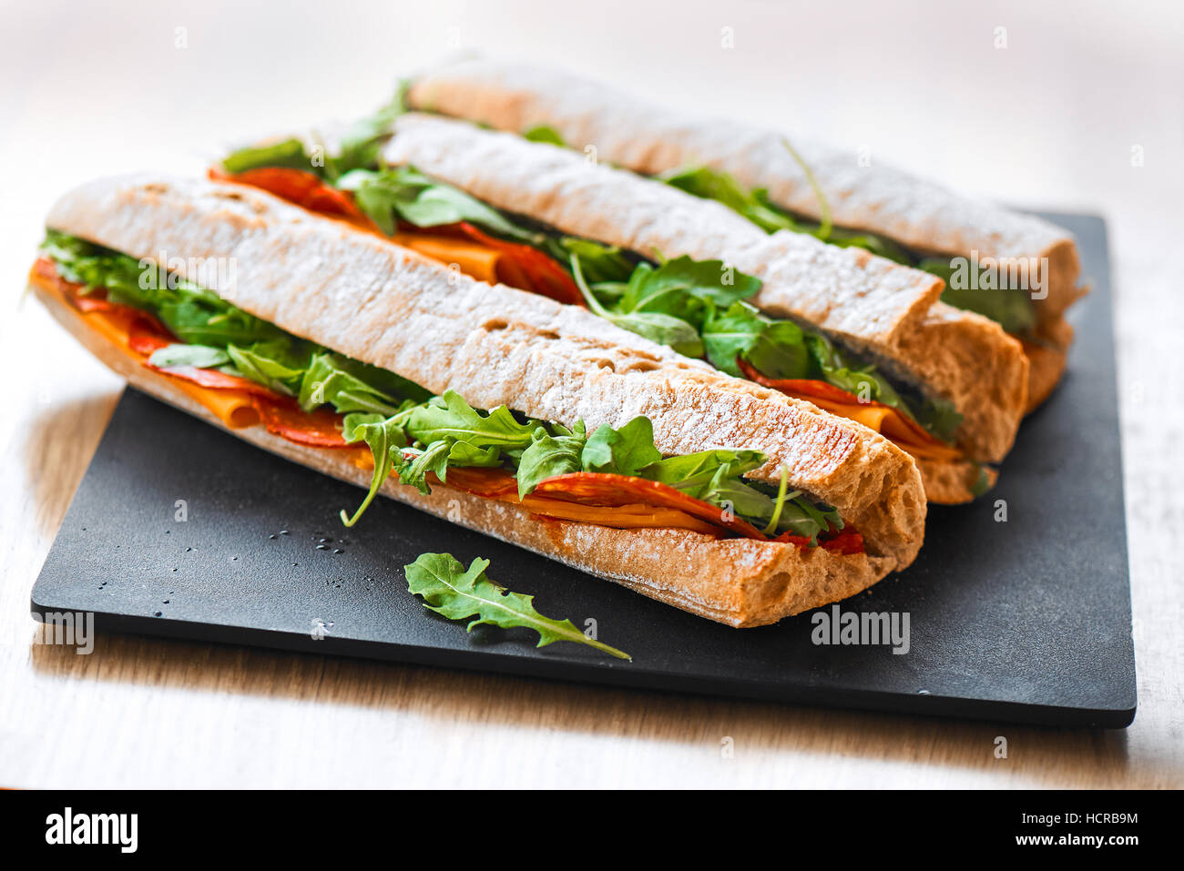 Croûté frais sous-marin sain baguette sandwich au salami, fromage et roquette. Selective focus Banque D'Images