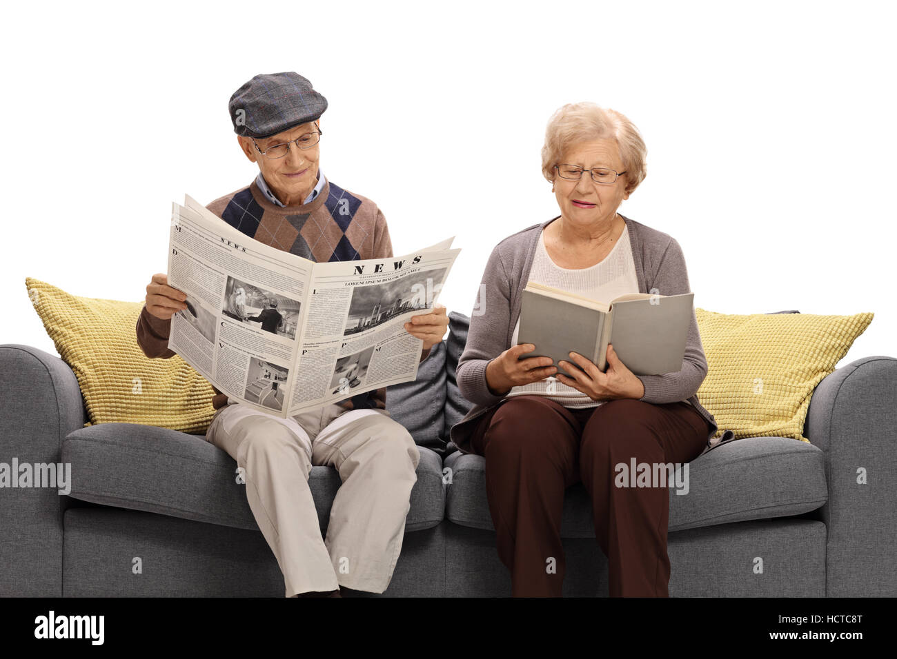 Un homme âgé assis sur un canapé et lire un journal avec une vieille femme lisant un livre isolé sur fond blanc Banque D'Images