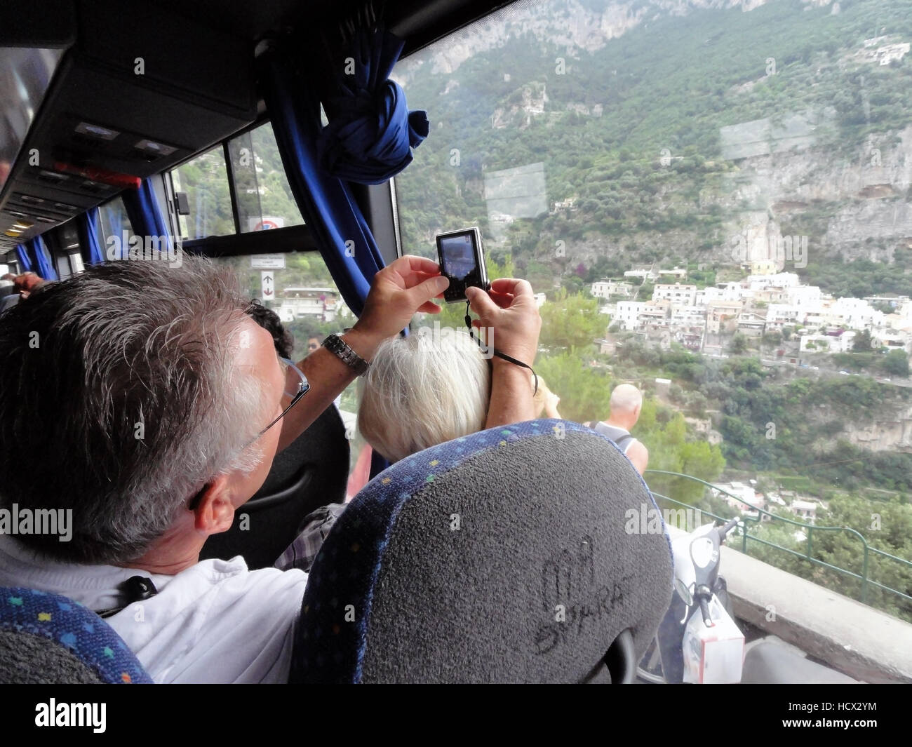 Cet homme prend une photo par la fenêtre d'un bus et en poussant son passager à l'écart. Banque D'Images