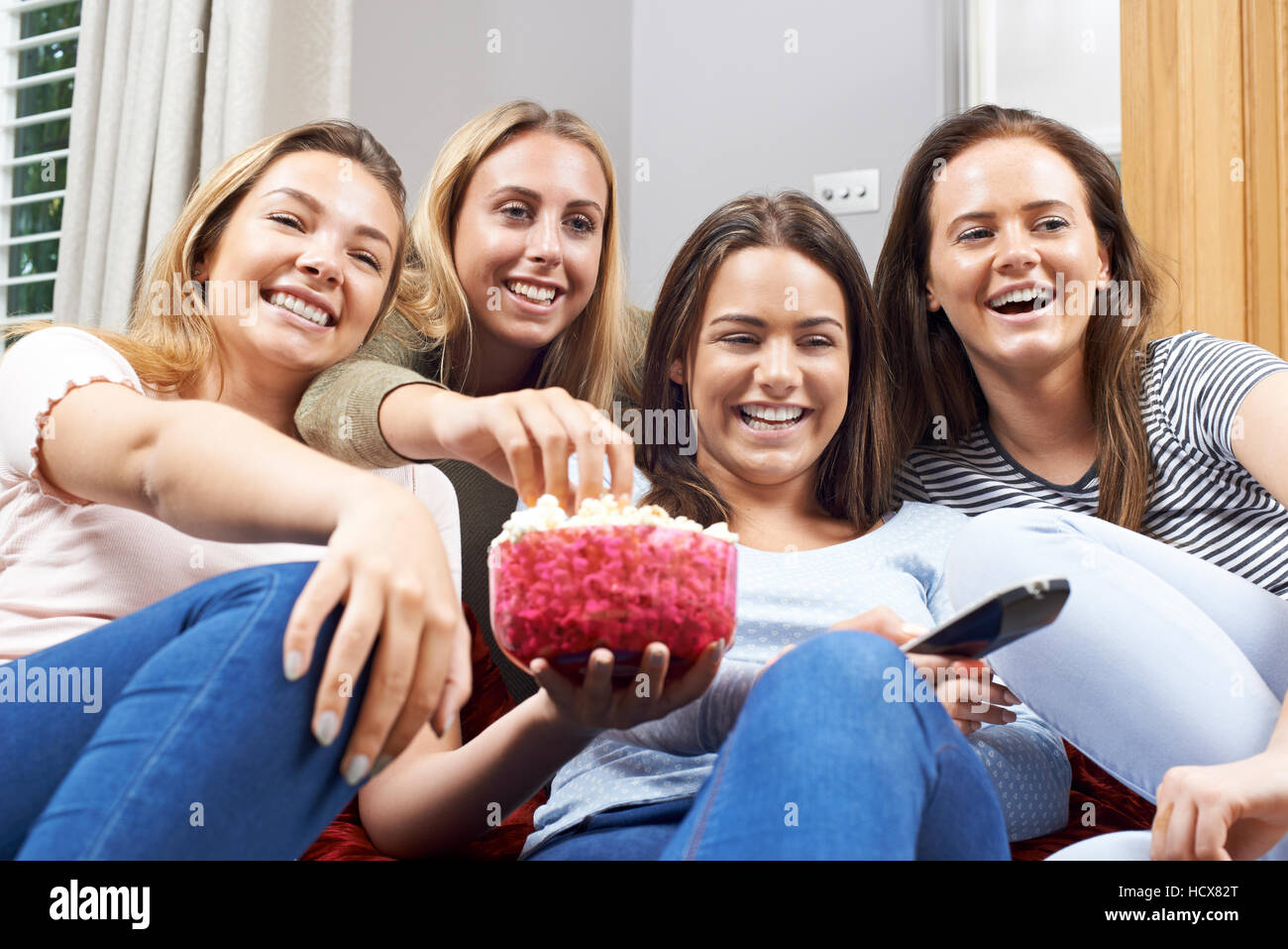 Groupe de femmes amis adolescents regardent la télévision à la maison Banque D'Images