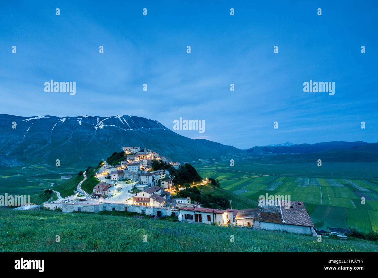 Crépuscule sur le village médiéval entouré de champs verts, Castelluccio di Norcia, Province de Pérouse, Ombrie, Italie Banque D'Images