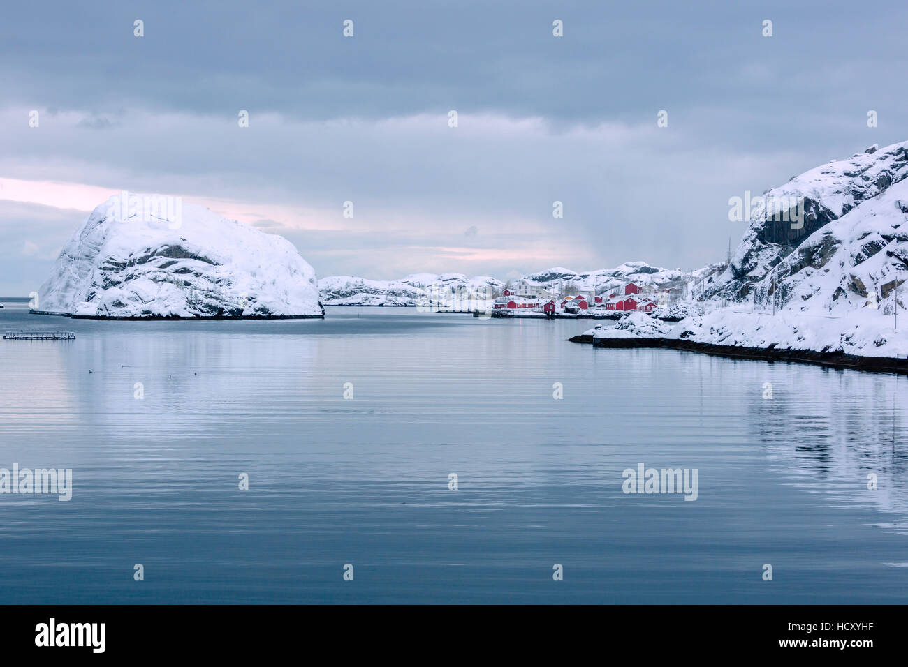 La mer froide du châssis et des sommets enneigés le village de pêcheurs au crépuscule, Nusfjord, Nordland, îles Lofoten, dans le Nord de la Norvège Banque D'Images