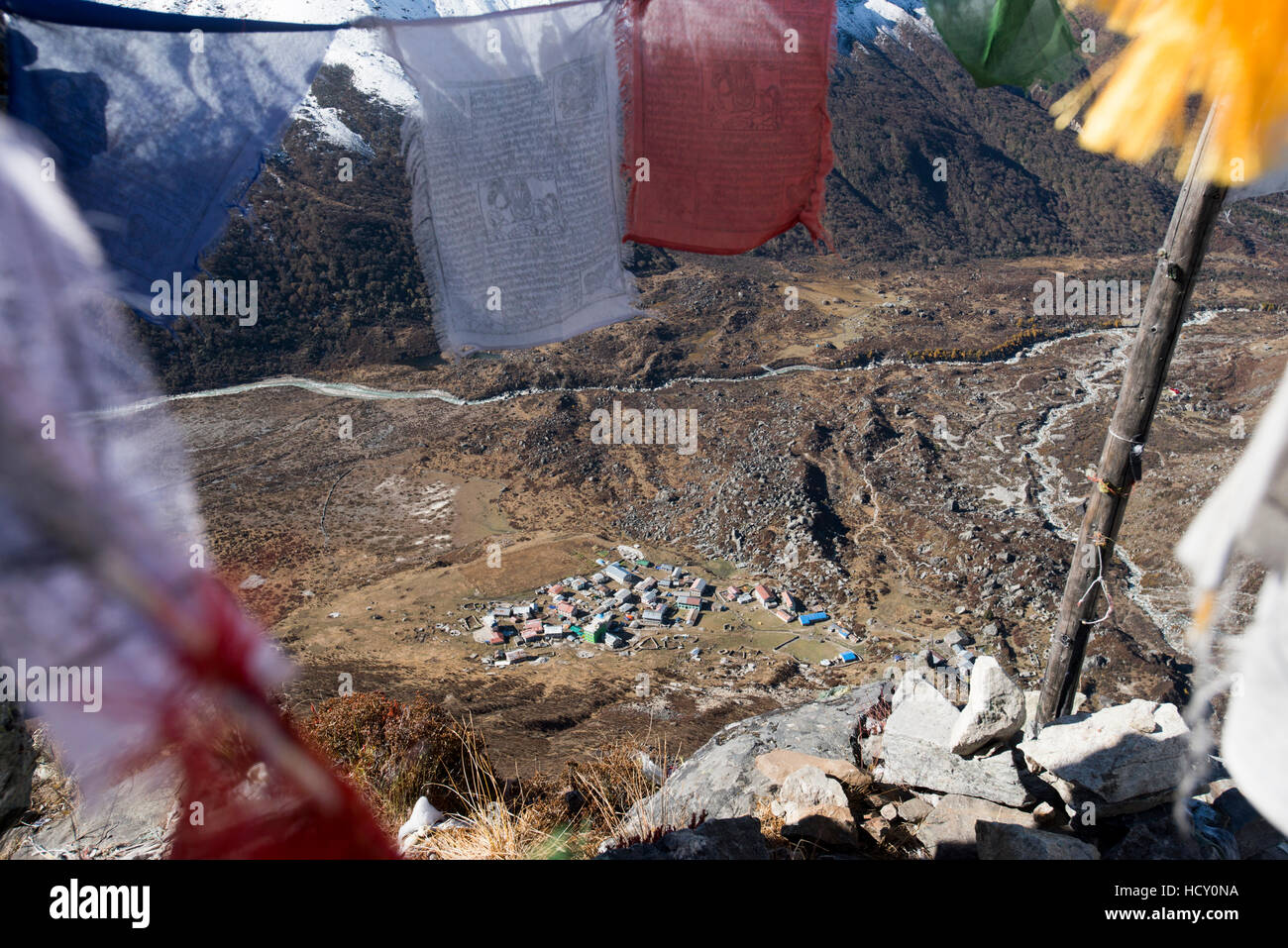 Kyanjin Gompa de vue dans la vallée de Langtang, vu à travers les drapeaux de prières bouddhistes sur le haut de Kyanjin Ri, Langtang, Népal Banque D'Images