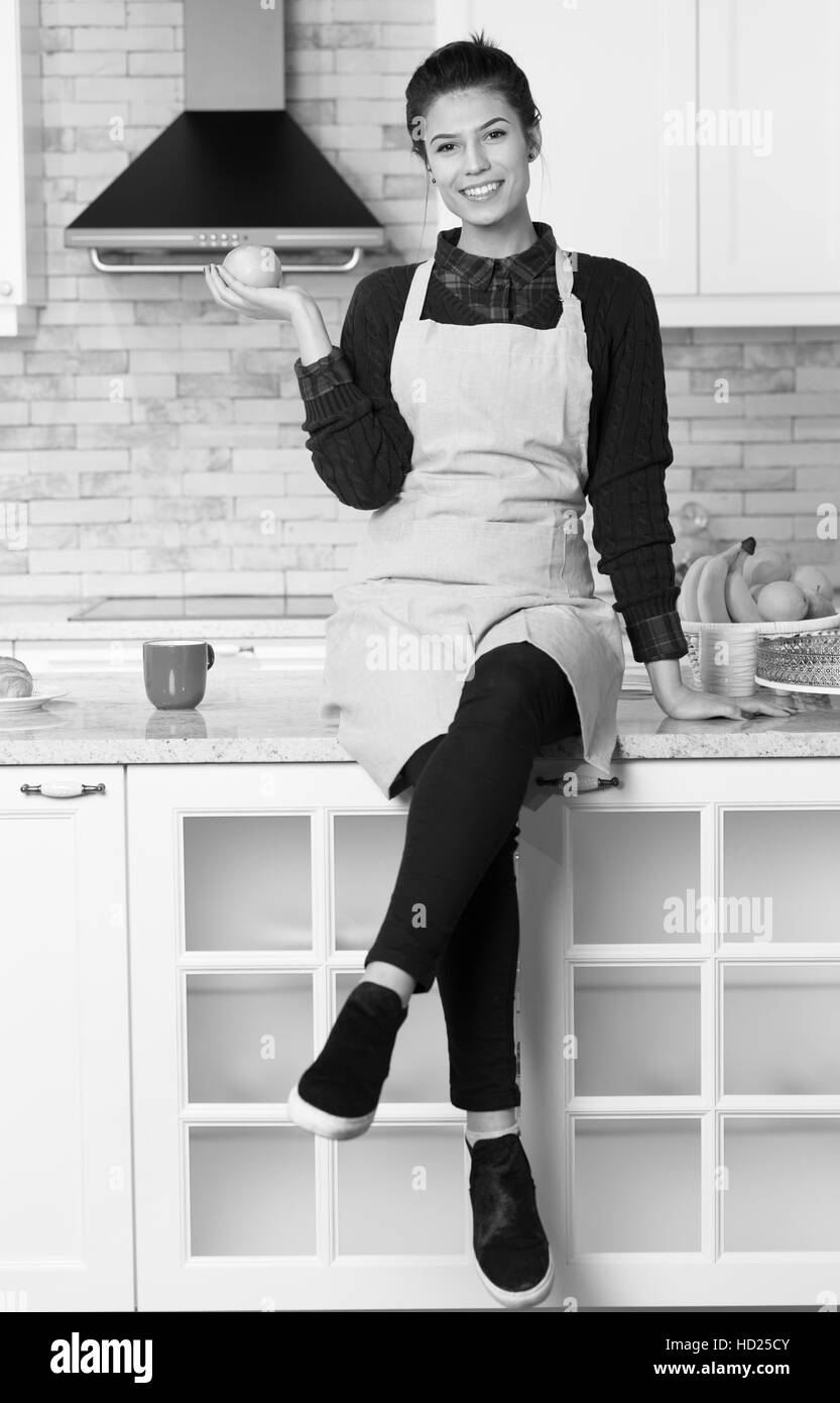 Happy young woman eating apples on cuisine Banque D'Images