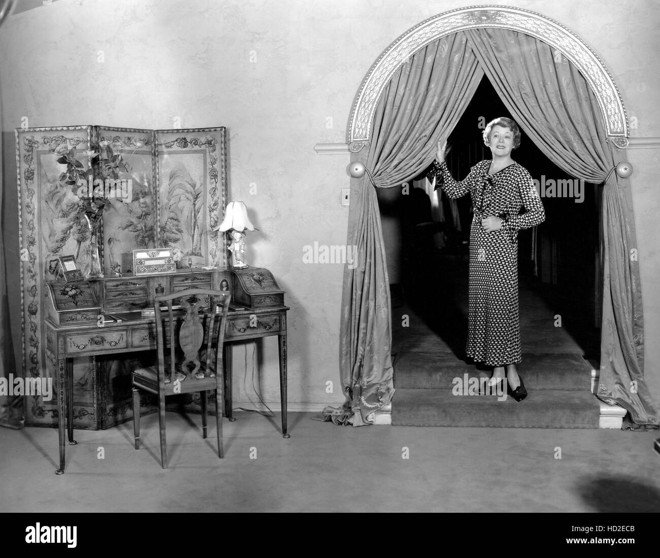 Mary Boland debout dans archway par salle de séjour à la maison, ca. 1934 Banque D'Images