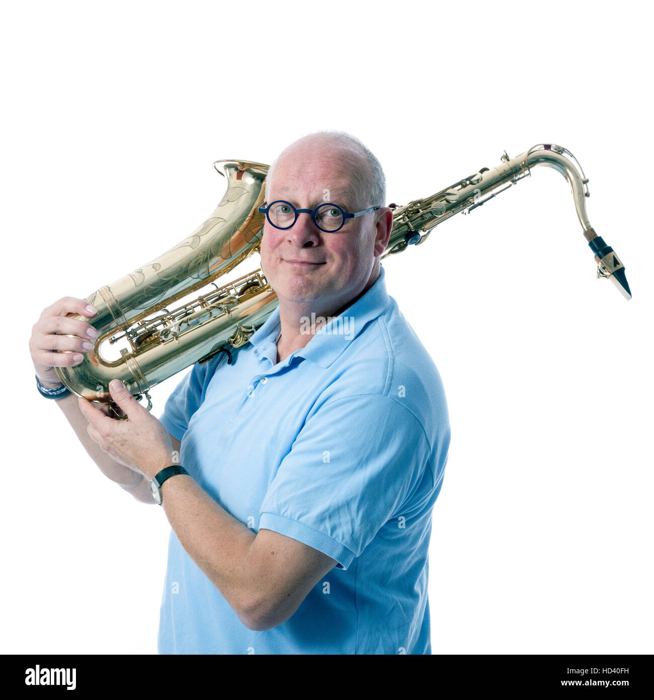 Homme d'âge moyen en bleu porte saxophone ténor sur l'épaule contre l'arrière-plan blanc studio Banque D'Images