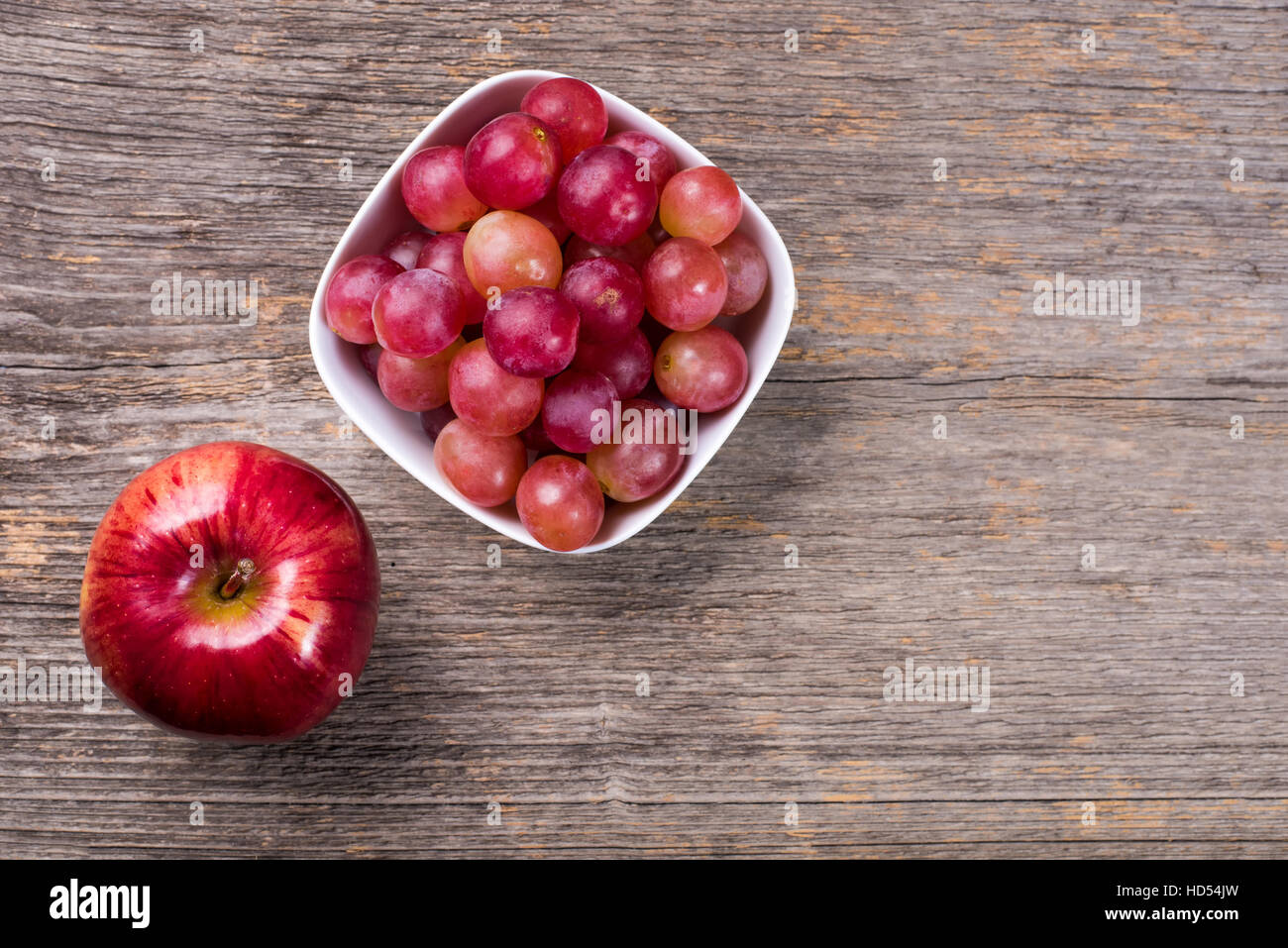 Les raisins dans un bol et Apple sur la table en bois dans la lumière naturelle Banque D'Images