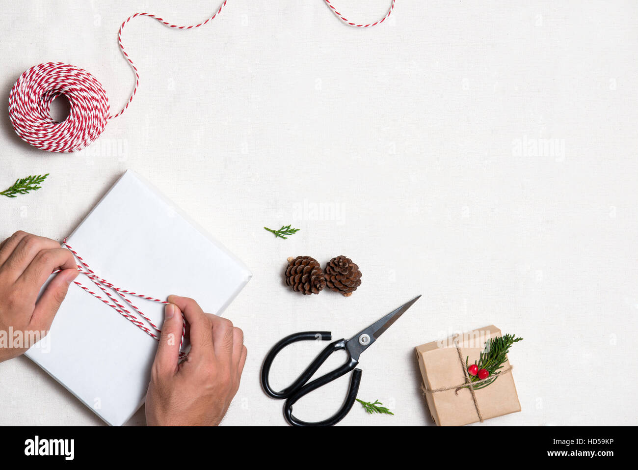 L'emballage des cadeaux de Noël les mains des hommes. Colis emballé dans du papier kraft à égalité avec le jute Banque D'Images
