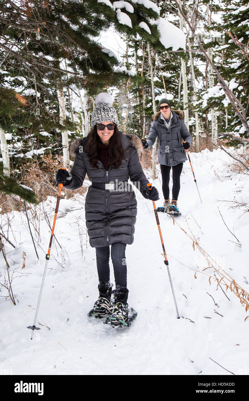 Un jeune couple heureux sur une randonnée en raquettes à Park City, Utah près de Deer Valley Resort. Le sentier serpente à travers les arbres à feuillage persistant, tremble, et brosse à Banque D'Images