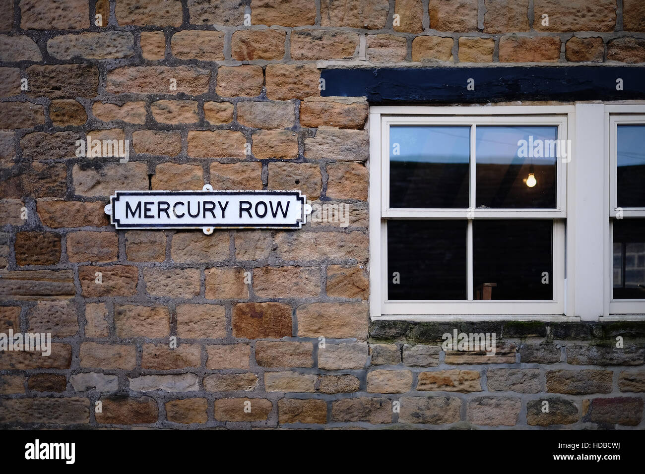 Mur en pierre du Yorkshire avec une fenêtre à guillotine en bois. Un signe de rue traditionnels est fixé au mur indiquant la ligne de mercure. Banque D'Images