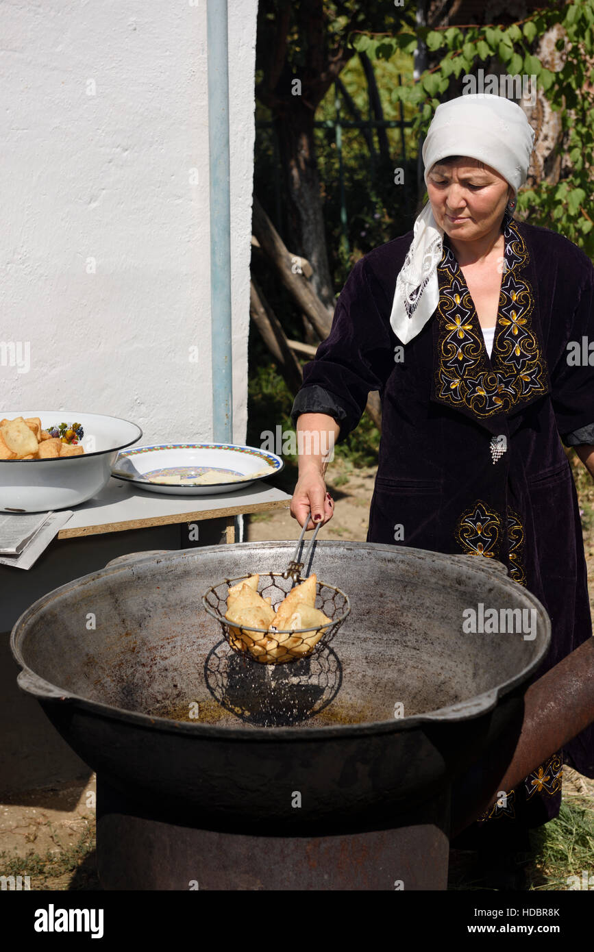 Femme Kazakh vidange de l'huile à partir de pâte frits à l'extérieur dans le Kazakhstan Shymkent Banque D'Images