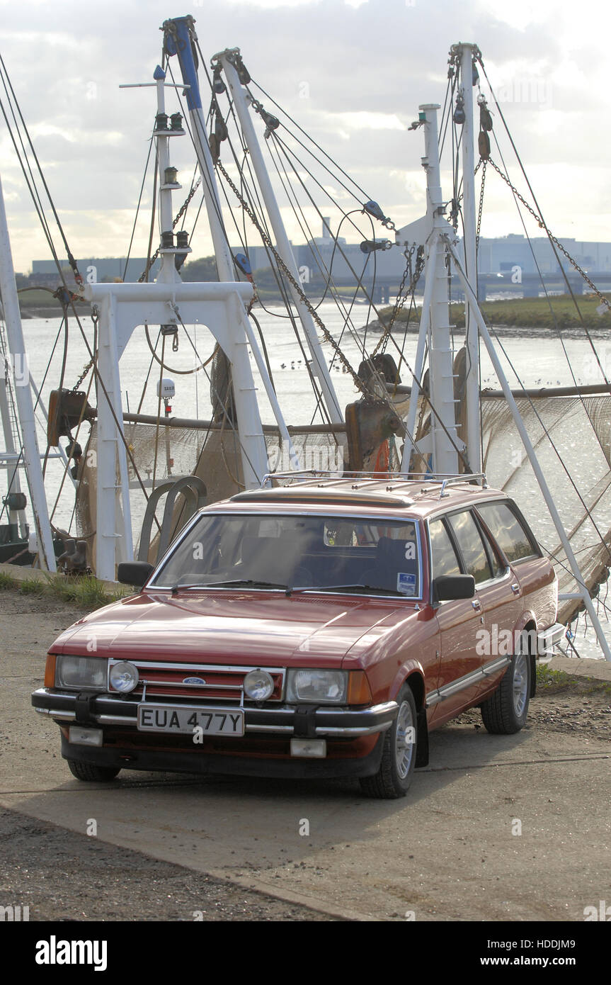 Ford Granada break sur quai avec des bateaux de pêche derrière Banque D'Images