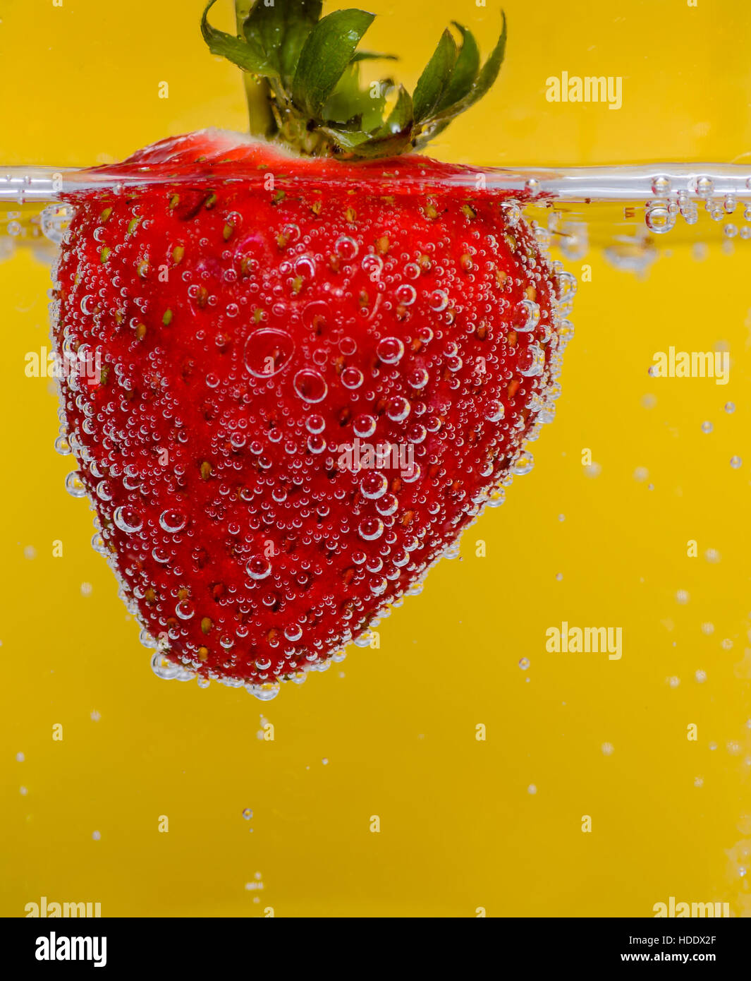 Dans l'eau pétillante aux fraises sur fond jaune Banque D'Images