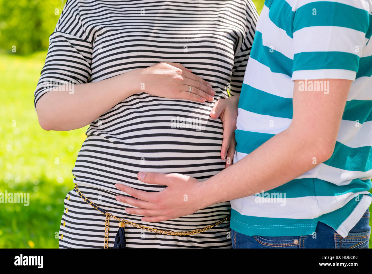 Les futurs parents mains caressant le ventre tourné dans un parc, close-up Banque D'Images