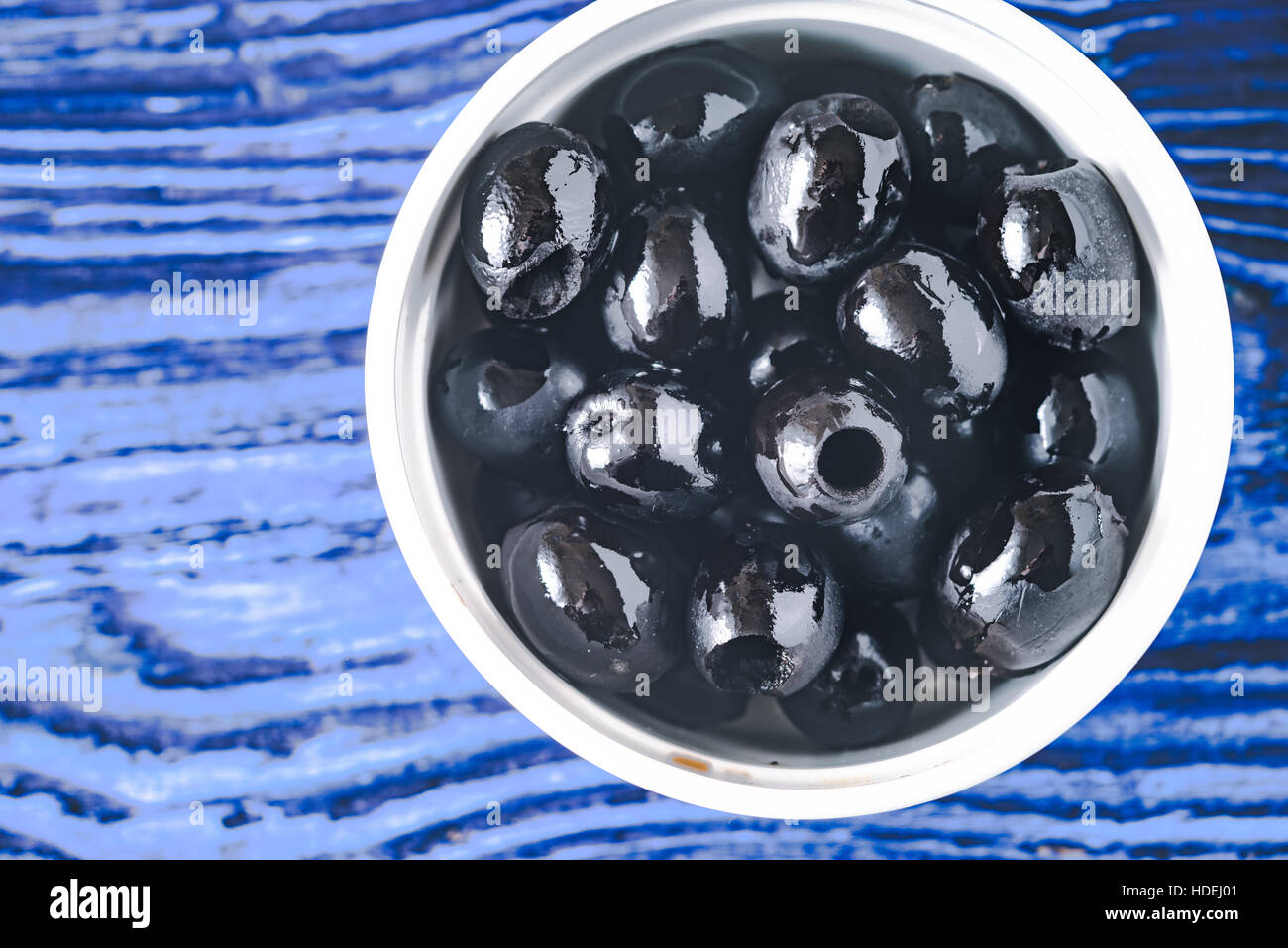 Olives noires dans le bol sur le fond bleu Vue de dessus Banque D'Images