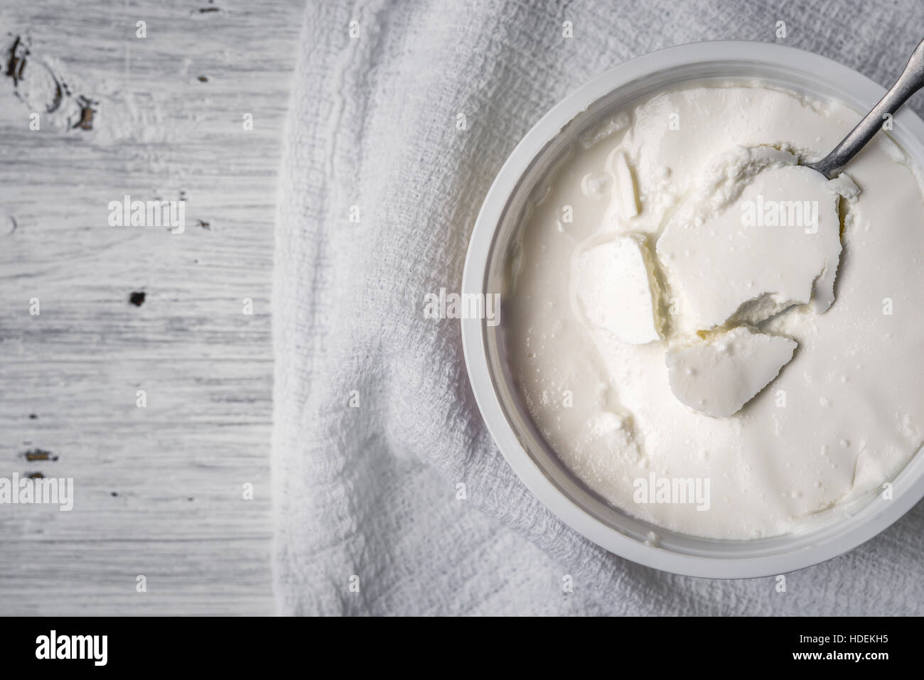 Fromage frais avec cuillère et serviette sur la vue de dessus de table en bois blanc Banque D'Images