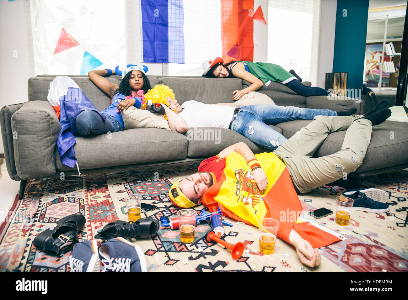 Groupe d'amis de dormir dans une salle de séjour après soirée - partisans ivres se reposant après la célébration de leurs équipes à un événement sportif Banque D'Images