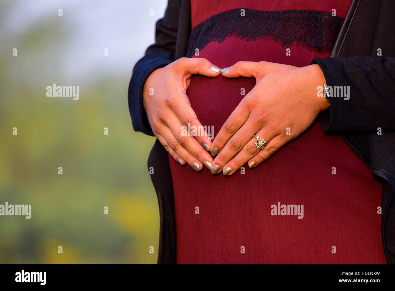 L'analyse d'une maternité femme enceinte de huit mois, portant une belle robe à un emplacement en extérieur Banque D'Images
