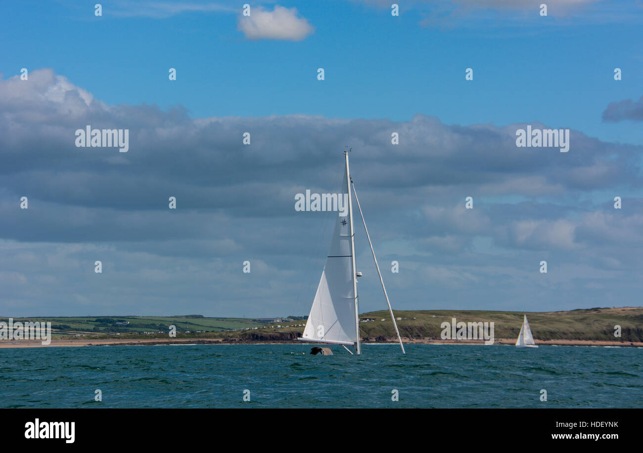 Houle de mer bleu azur masquent la coque d'un bateau à voile. ciel bleu et nuages moelleux de pembrokeshire typique journée d'été. Banque D'Images