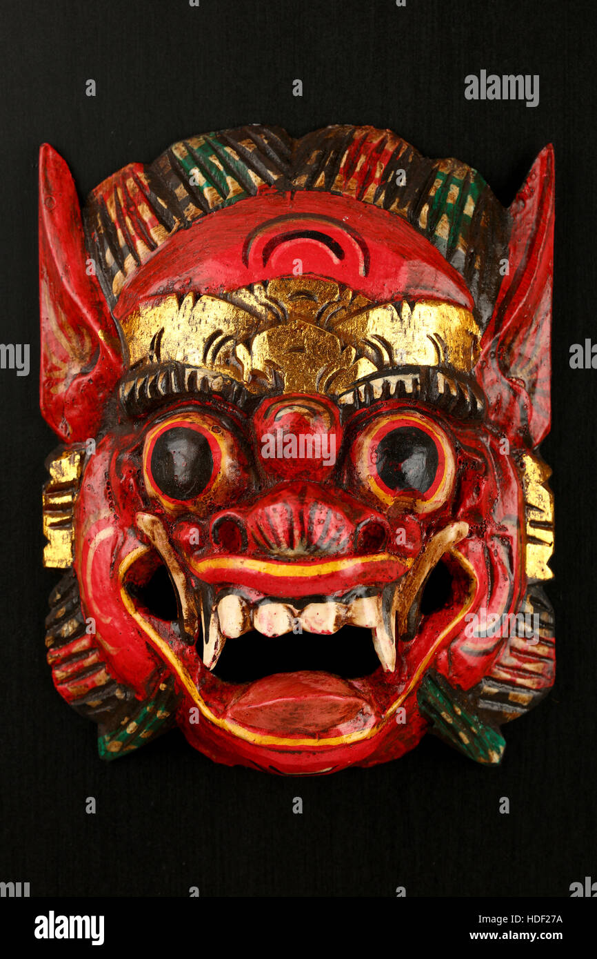 En bois traditionnel asiatique peint rouge avec masque de visage de démon, dragon ou lion mythique peint sur fond noir Banque D'Images