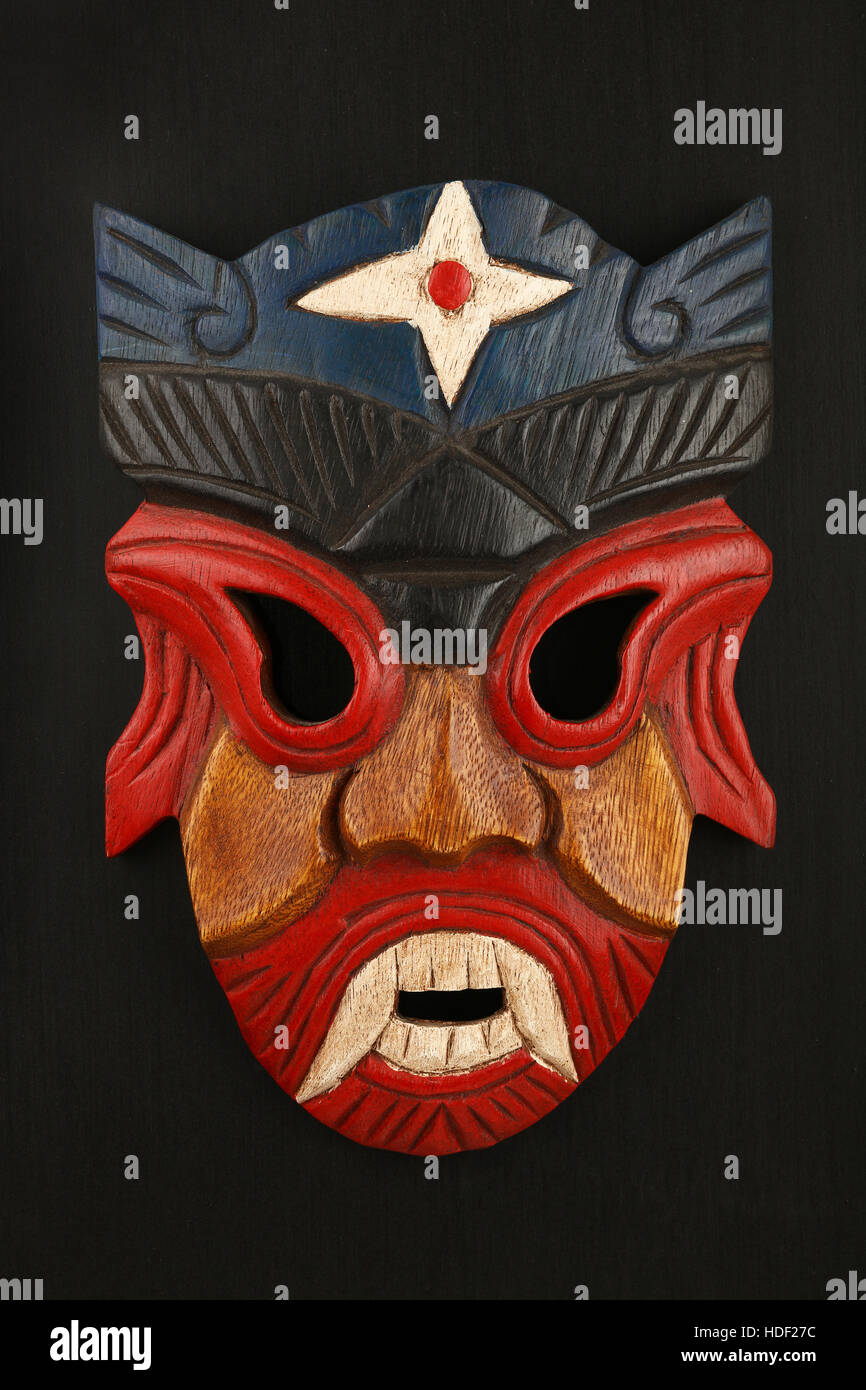 En bois traditionnel asiatique peint rouge et bleu avec masque de visage de l'homme ou démon sur fond noir Banque D'Images