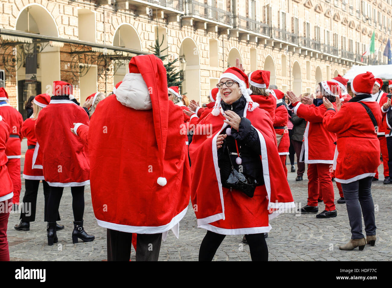 Les gens danser dans un carré avec le Père Noël costumes en Italie. Banque D'Images