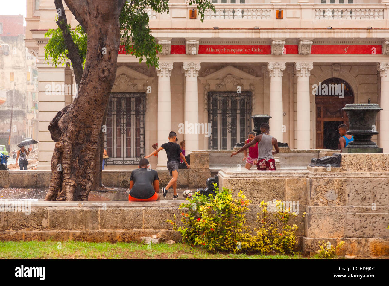 Les adolescents jouent au soccer (football) dans la pluie le long de Paseo de Marti dans la Vieille Havane, Cuba. Banque D'Images