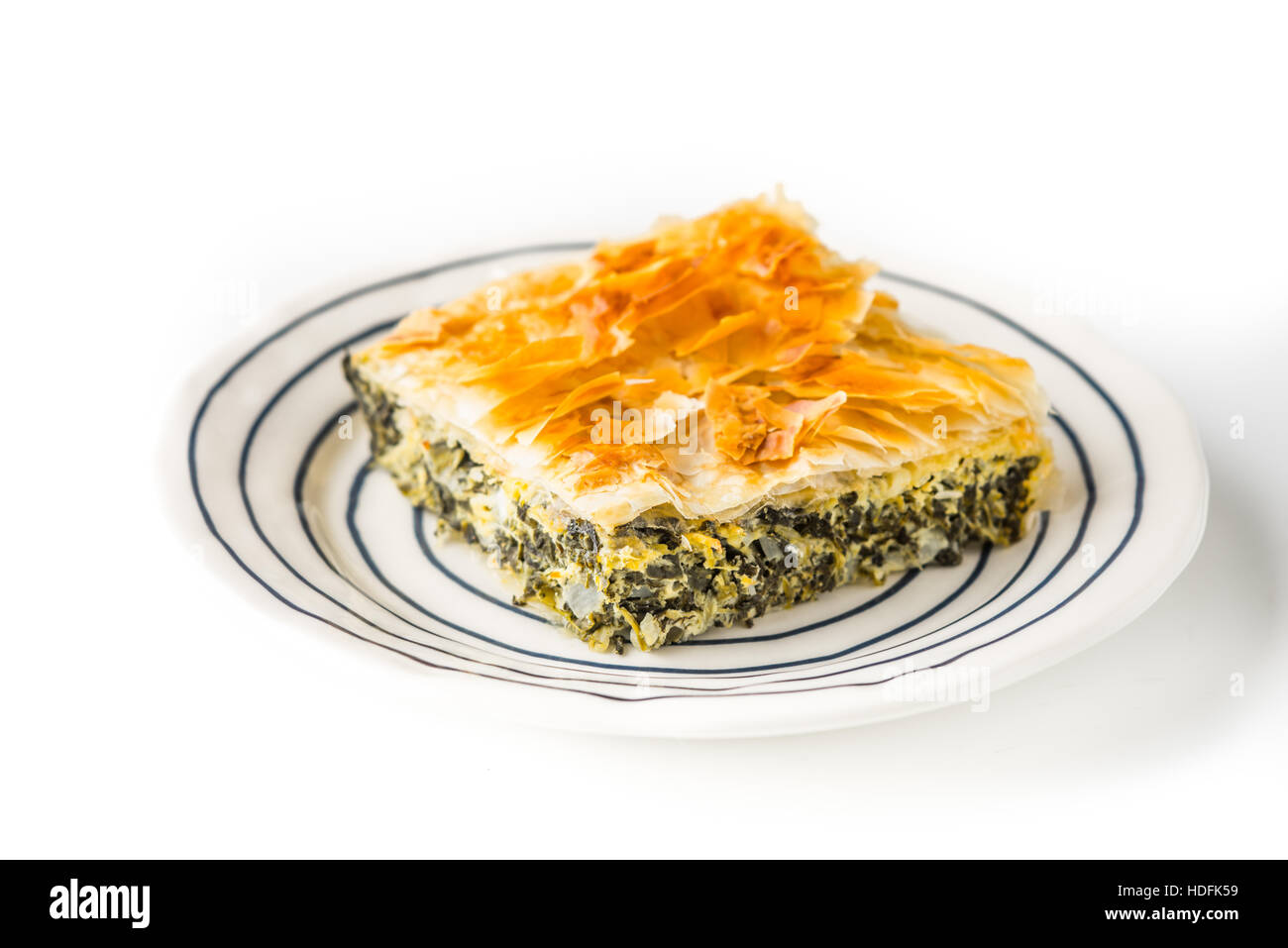 Morceau de tarte spanakopita grecs sur la plaque en céramique sur le fond blanc Banque D'Images