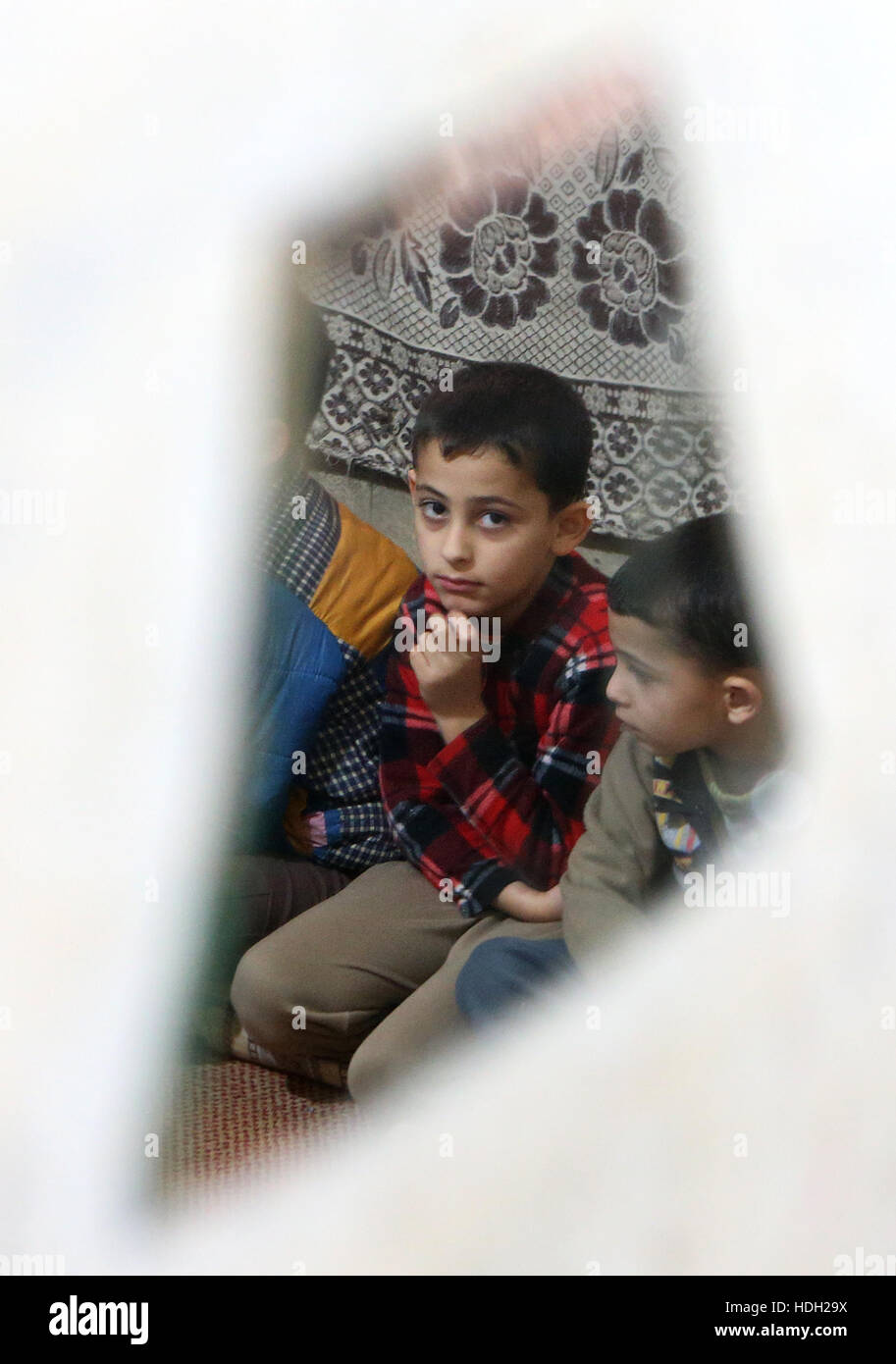 Réfugié syrien Omar Al Rahal, 9, se reflète dans un miroir brisé comme il est assis aux côtés de ses frères dans un appartement à Tripoli, au Liban, après la famille a fui leur maison à Homs, en Syrie. Banque D'Images