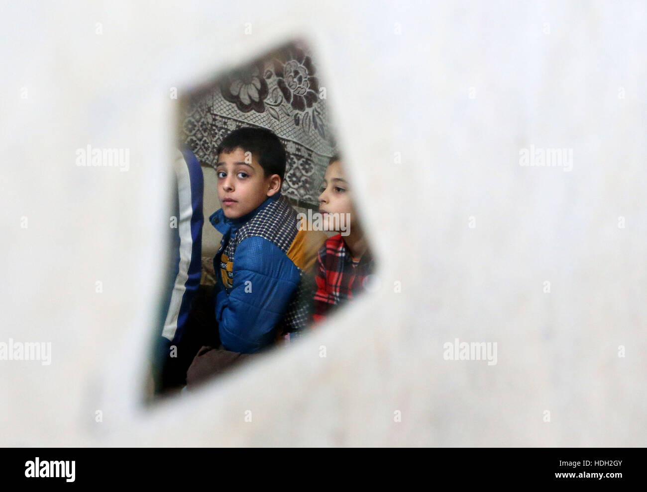 Réfugiés syriens Baker Al Rahal, 10, se reflète dans un miroir brisé comme il est assis aux côtés de ses frères dans un appartement à Tripoli, au Liban, après la famille a fui leur maison à Homs, en Syrie. Banque D'Images