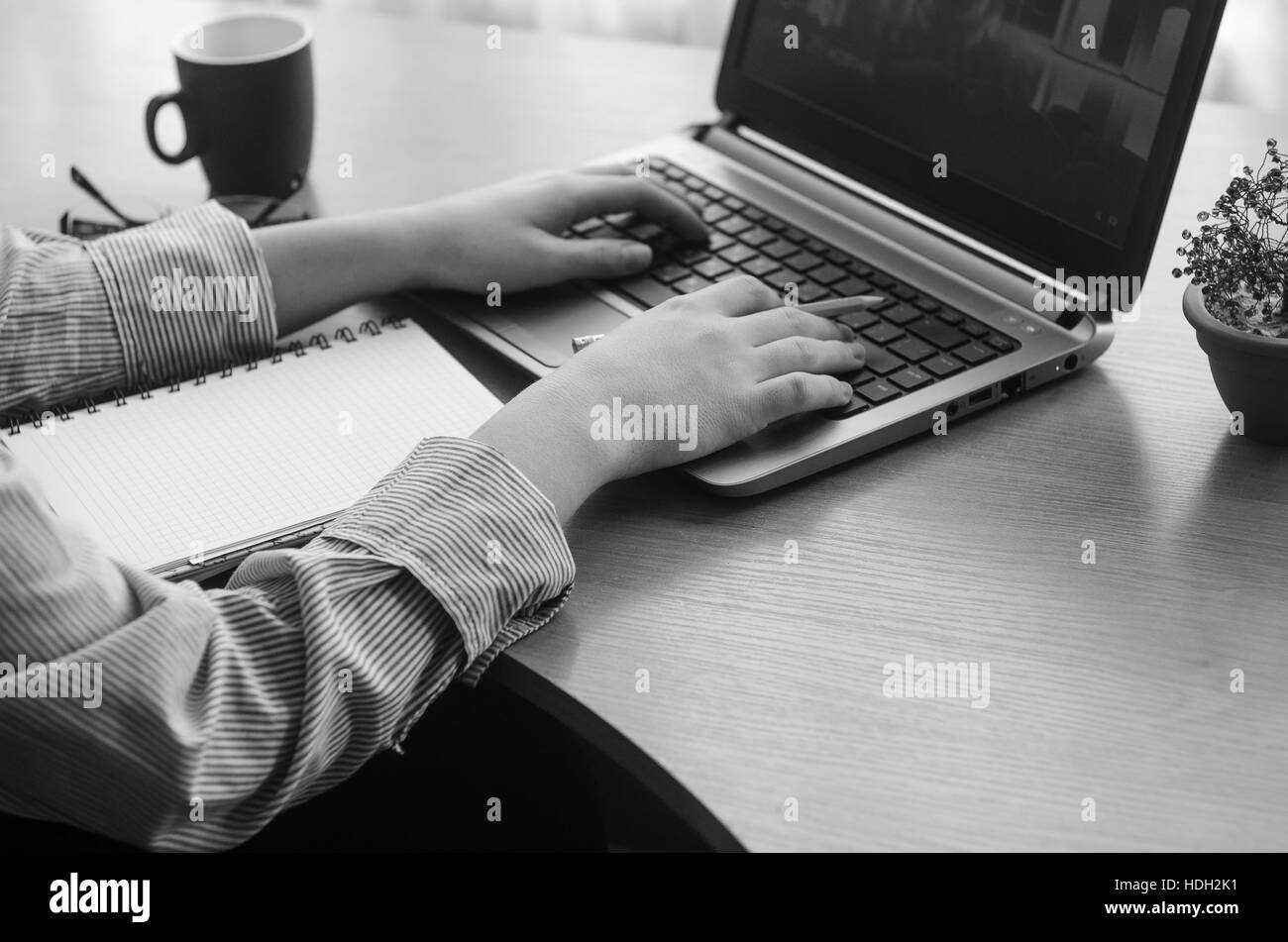 Les mains de la jeune femme travaillant sur un ordinateur portable, d'image en noir et blanc Banque D'Images