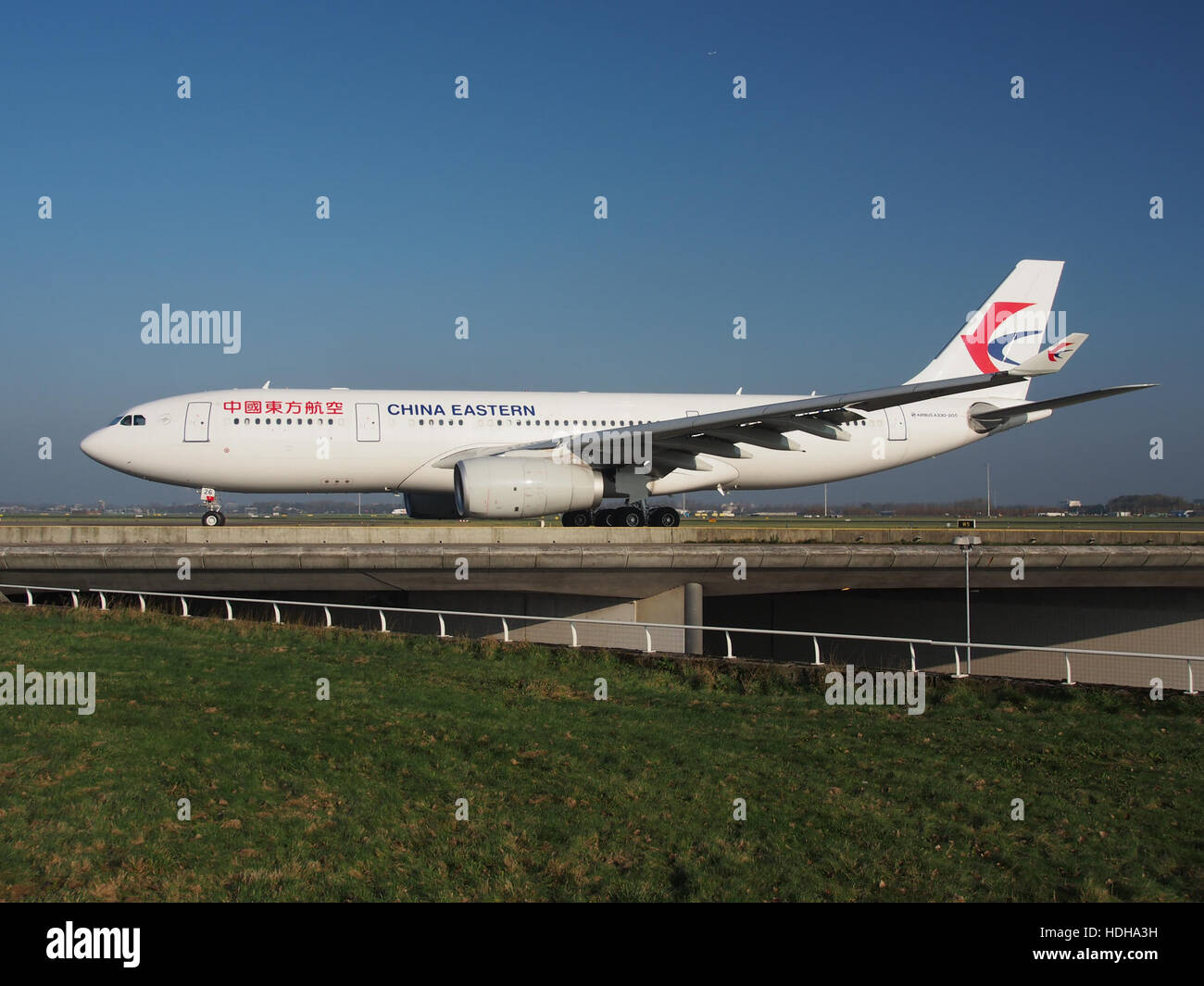 L'image montre un Airbus A330-243 de China Eastern Airlines à l'aéroport de Schiphol, circulant vers la piste 36L. Cet avion de ligne moderne fait partie de la flotte desservant les vols internationaux de China Eastern Airlines. Banque D'Images