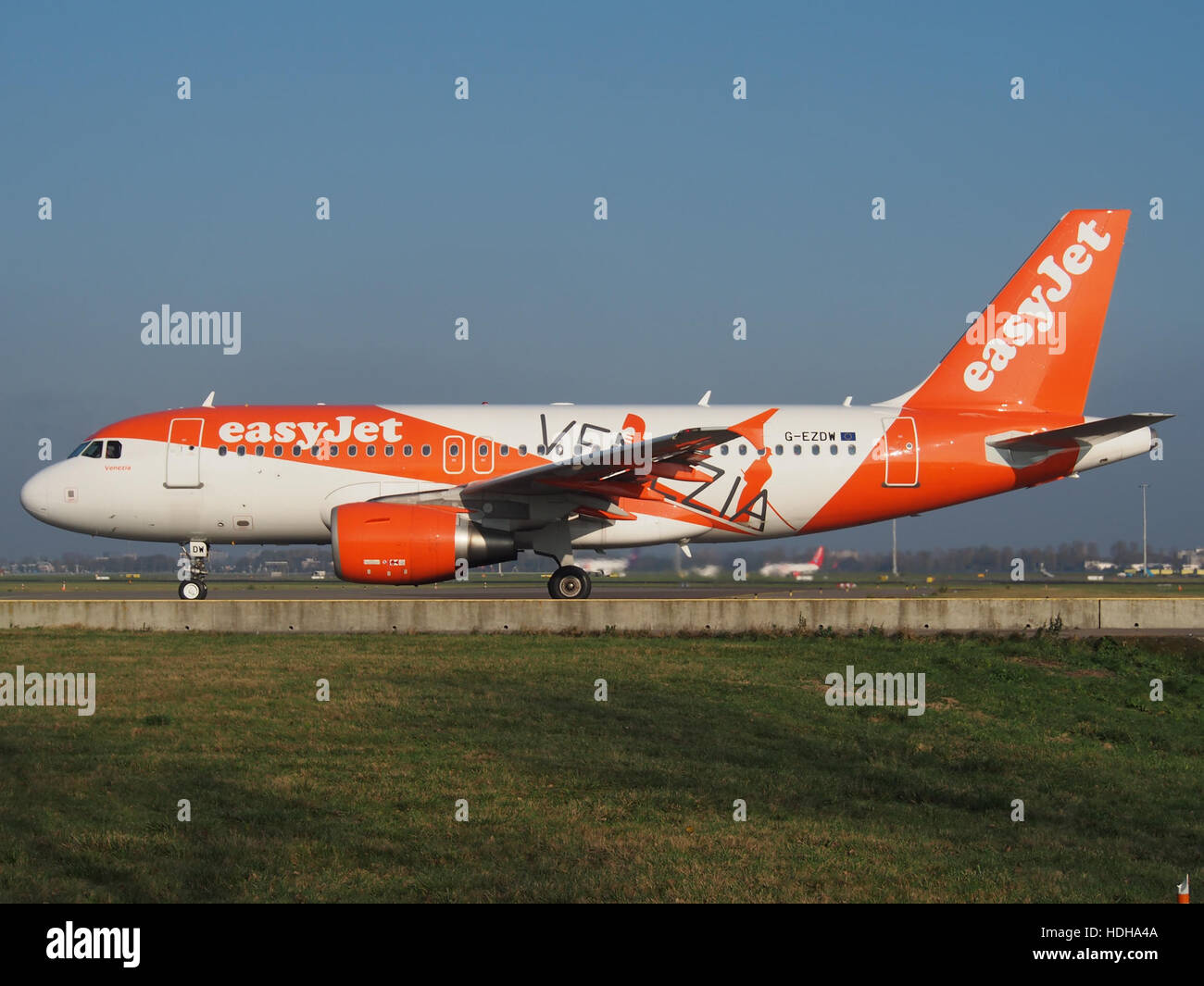 L'Airbus A319-111, immatriculé G-EZDW, exploité par EasyJet, est vu rouler en direction de la piste 36L à l'aéroport de Schiphol. Cet avion fait partie de la flotte d'EasyJet, qui dessert de nombreuses destinations européennes. L'A319 est connu pour son rendement énergétique et est largement utilisé dans les vols court-courriers. Banque D'Images