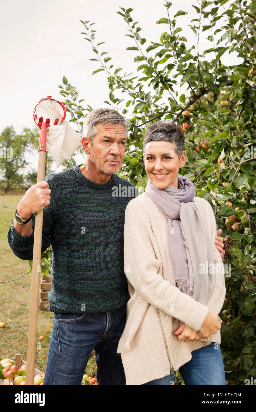 Portrait of happy woman standing avec l'homme dans le verger Banque D'Images