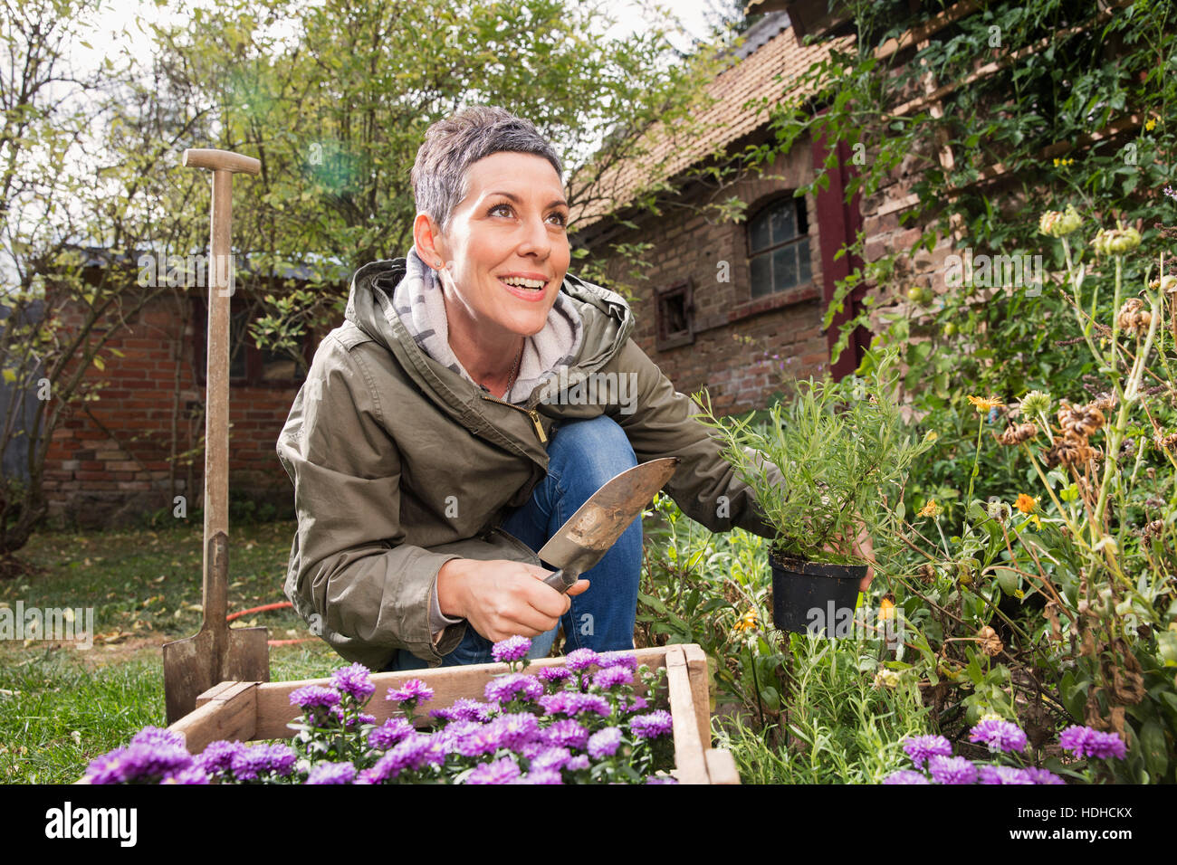 Happy woman holding truelle et de plantes en pot dans la cour arrière Banque D'Images