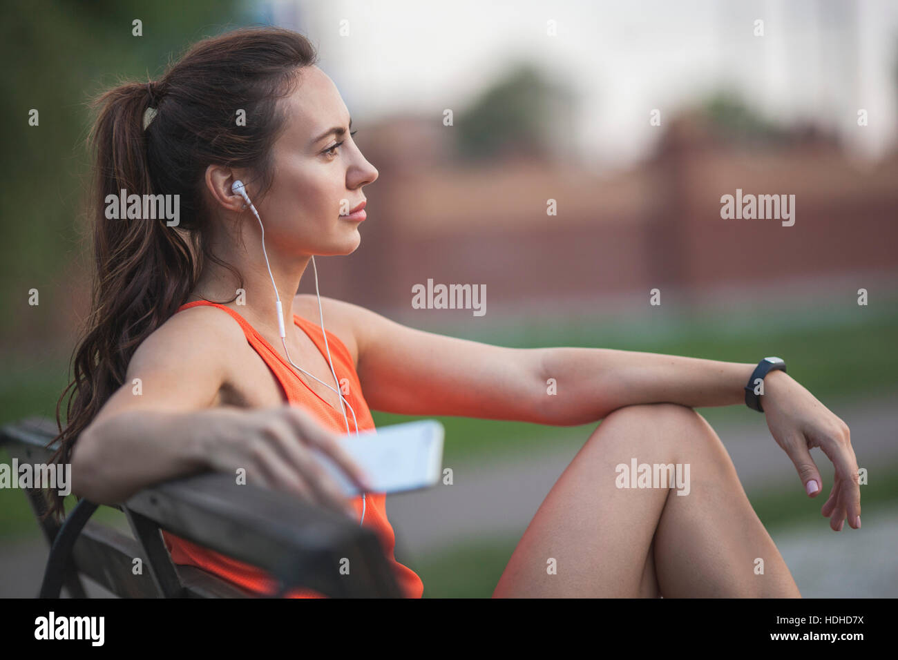 Femme assis sur un banc tout en écoutant de la musique au parc Banque D'Images
