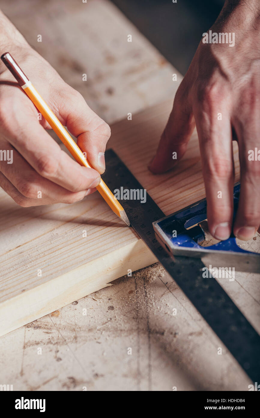 Les mains coupées de carpenter marquage sur plank avec crayon et règle à l'atelier Banque D'Images