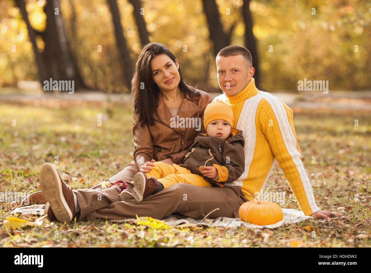 Portrait de parents assis avec mignon bébé garçon dans le parc en automne Banque D'Images
