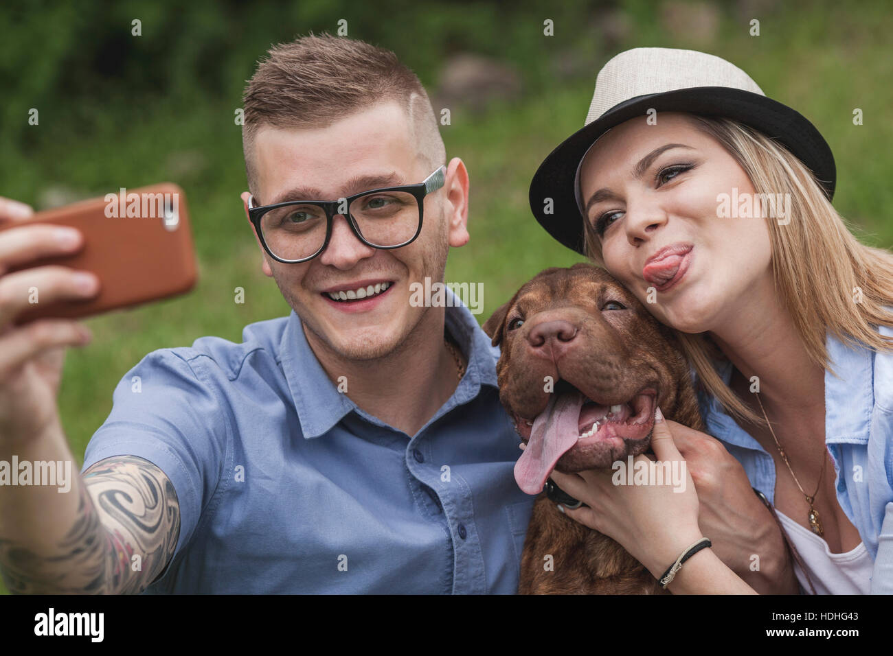 Un couple avec leur Shar-pei/Staffordshire Terrier chien dans le parc en prenant un selfies Banque D'Images