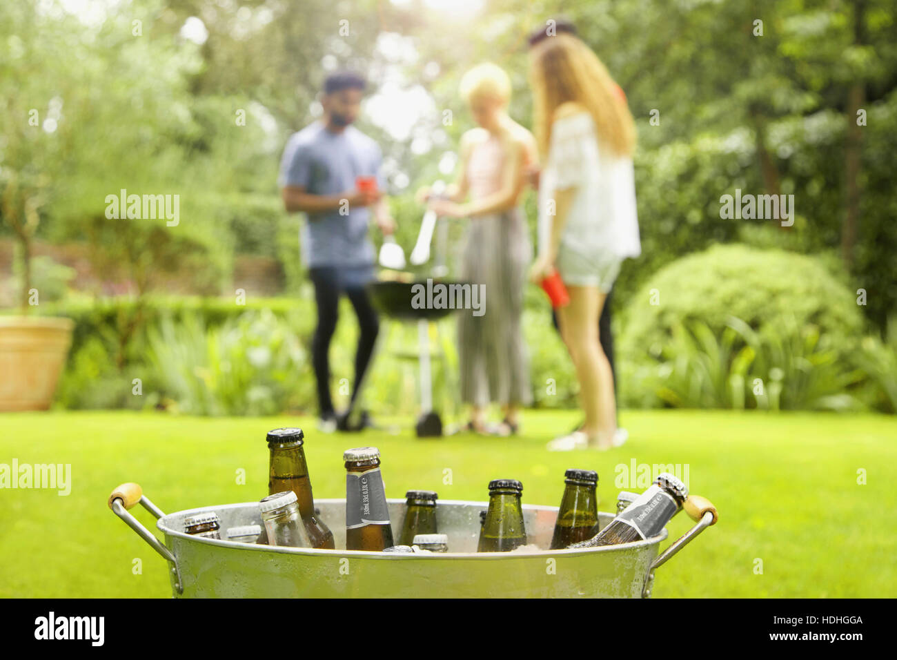 Les bouteilles de bière dans le godet tandis que friends enjoying barbecue party en arrière-plan à la cour Banque D'Images
