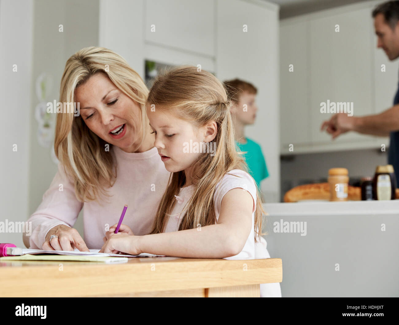 Une femme et sa fille assis à une table dans la cuisine à la recherche de ses devoirs. Banque D'Images