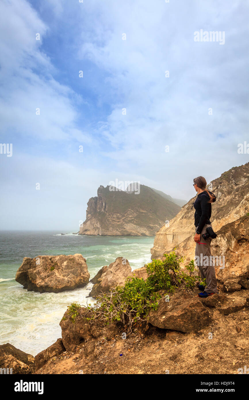 Femme photographe regardant la mer depuis un clif sur la côte d'Oman Banque D'Images