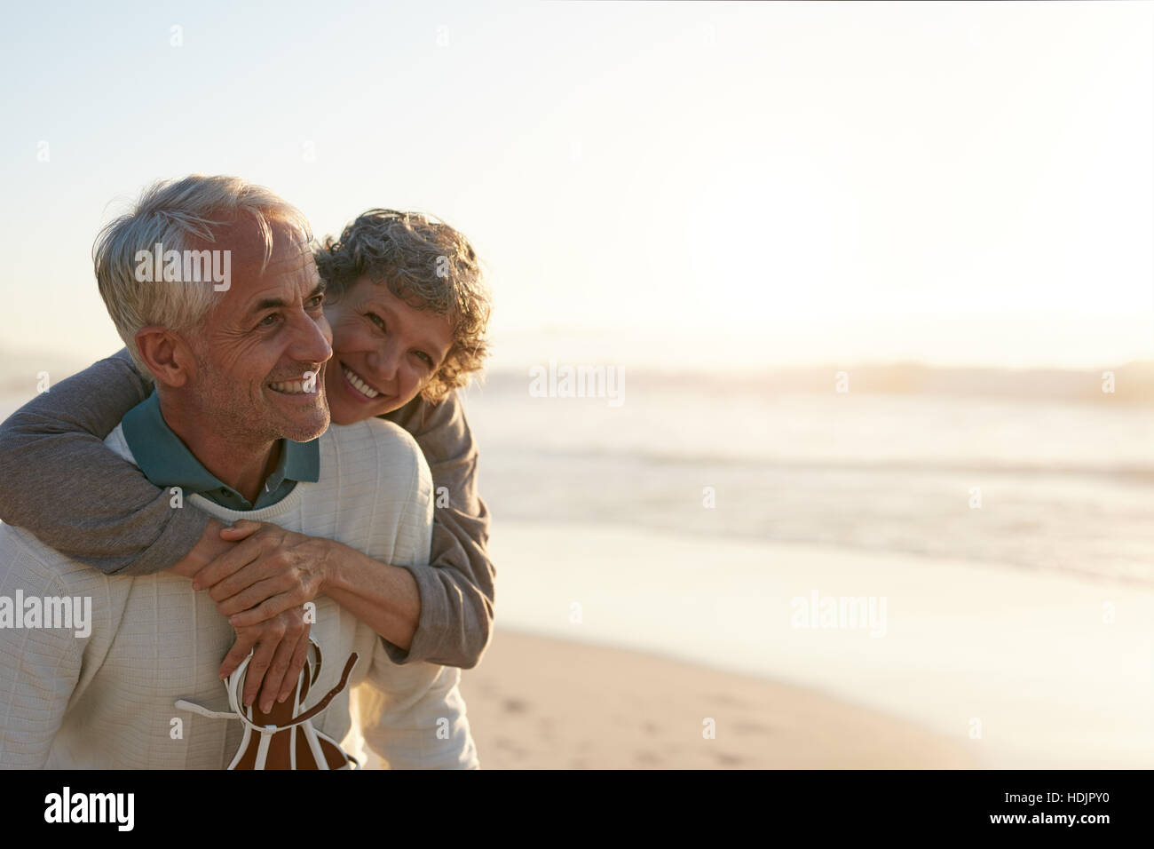 Portrait de senior homme d'être embrassé par sa femme à la plage. Surfers au bord de la mer. Banque D'Images