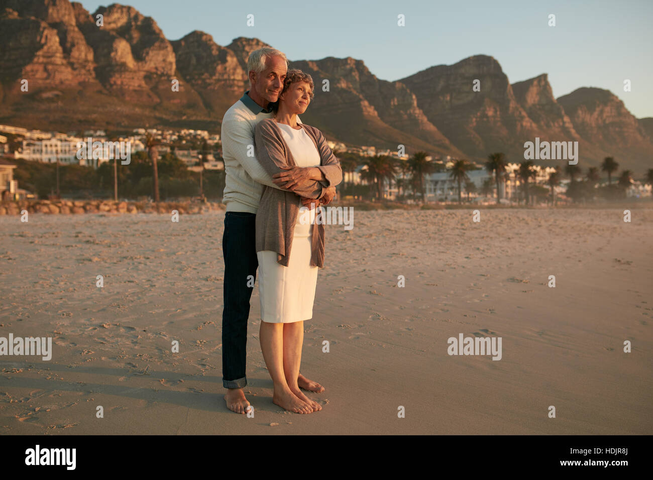Toute la longueur de balle senior couple embracing romantique au bord de la mer. Couple aimant profiter du coucher du soleil à la plage. Banque D'Images