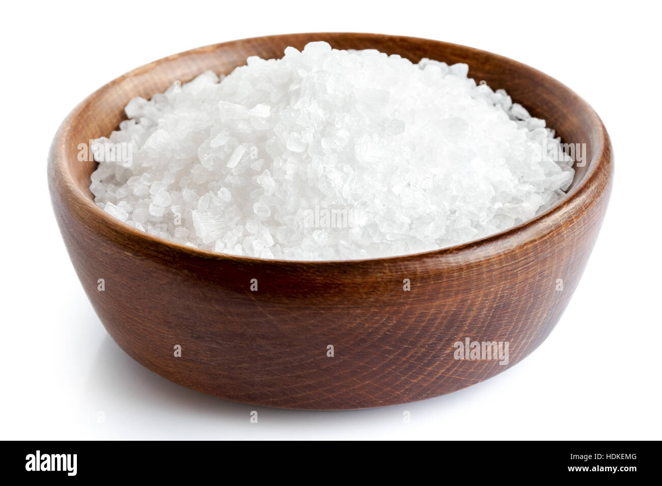 Le gros sel dans un plat en bois isolé sur blanc. Banque D'Images