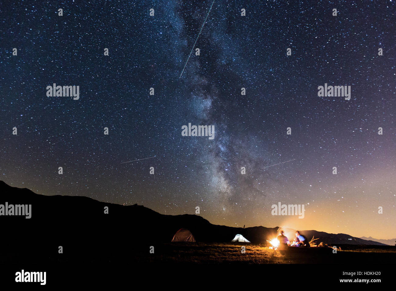 Voie lactée. Ciel de nuit avec des étoiles et silhouette de deux homme autour d'un feu Banque D'Images