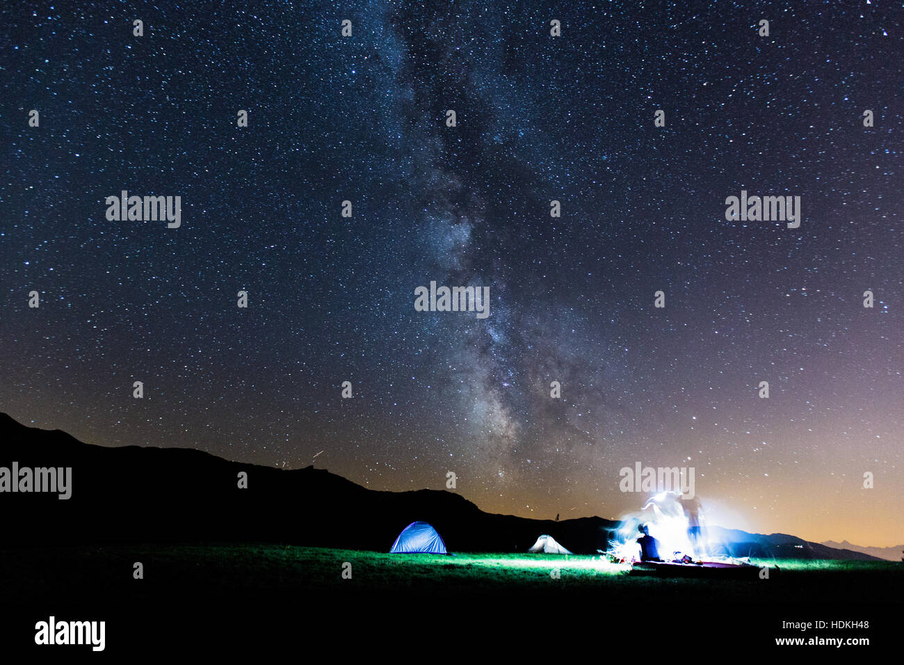 Voie lactée. Ciel de nuit avec des étoiles et silhouette de deux homme autour d'un feu Banque D'Images