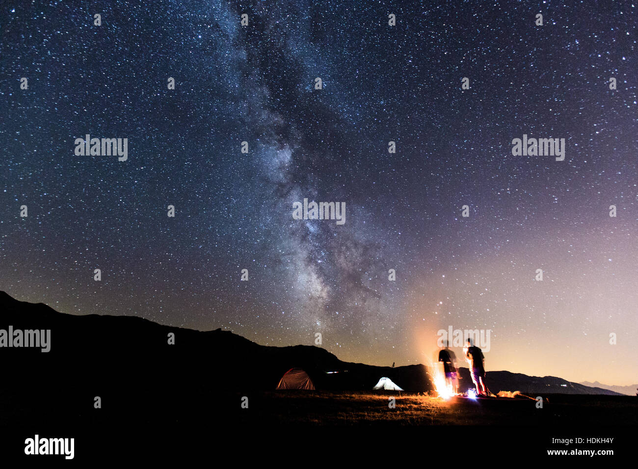 Voie lactée. Ciel de nuit avec des étoiles et silhouette de deux homme autour d'un feu Banque D'Images