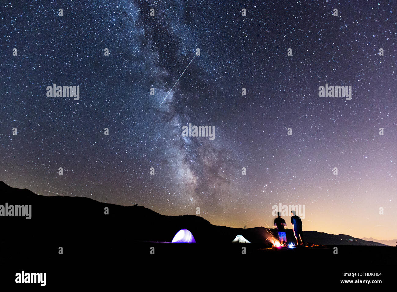 Voie lactée. Ciel de nuit avec des étoiles et silhouette de deux homme autour d'un feu Banque D'Images