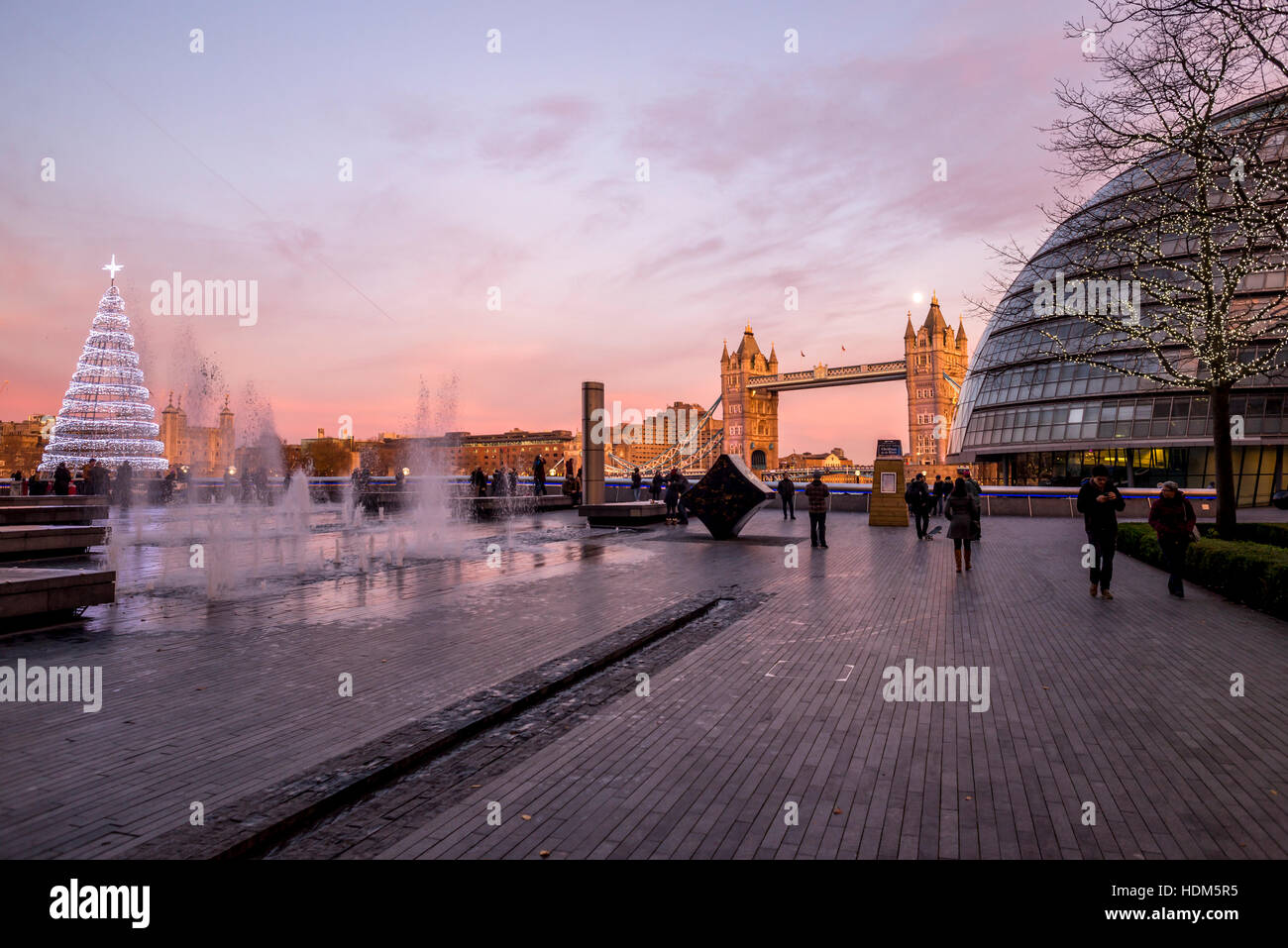 London Tower Bridge et le City Hall Building à un beau soir de pleine lune avec fontaines et d'arbres de Noël au premier plan. Banque D'Images